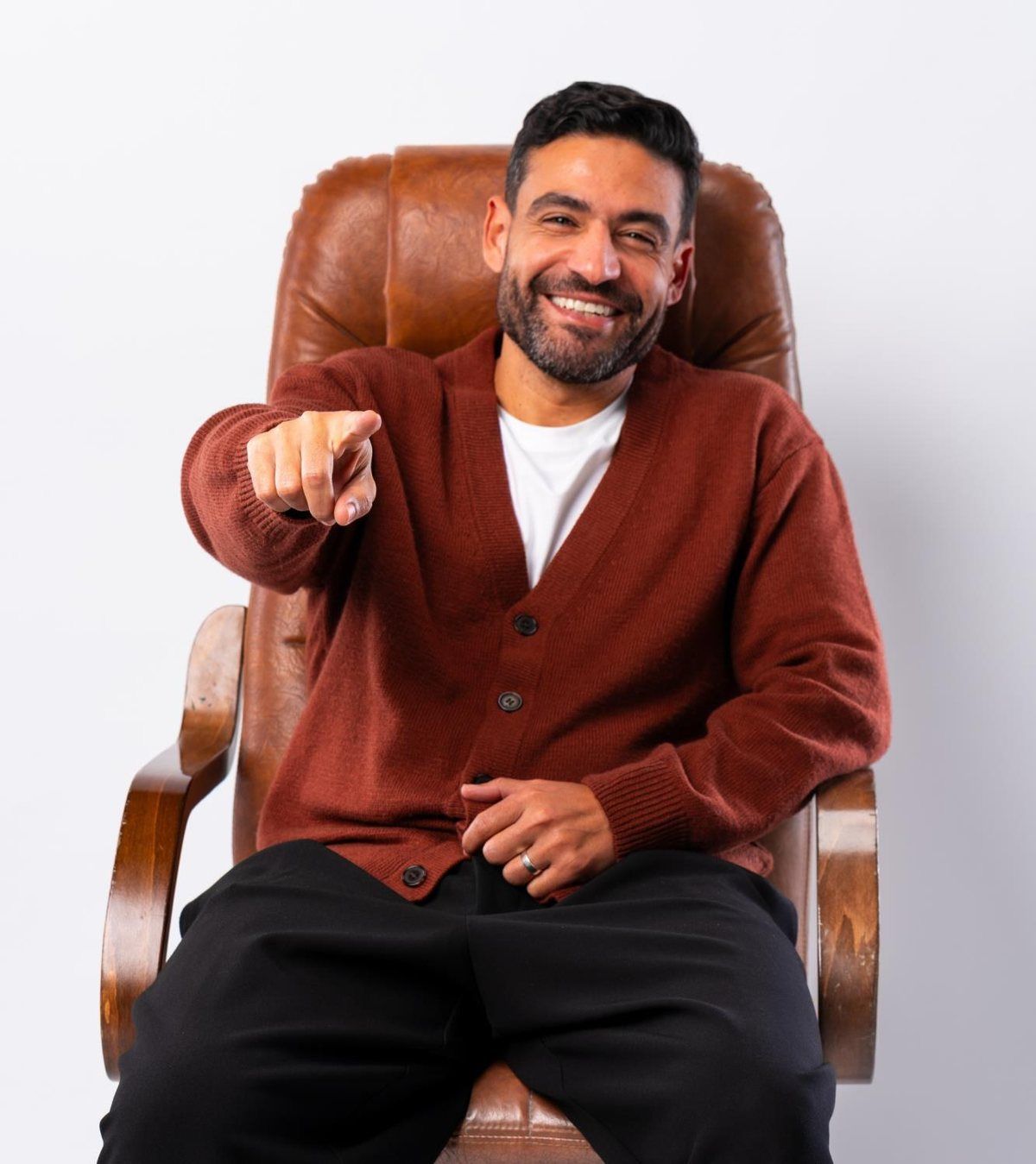 Islam Fawzy pointing at the camera from a leather armchair